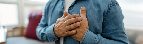 Close-up of a person’s folded hands wearing a denim shirt