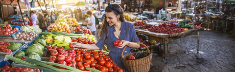 A woman buys vegetables at a market stall