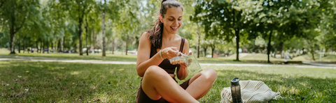 A woman is sitting in a meadow and looking at her cell phone