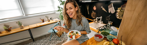 A woman is sitting at a table in a kitchen with a plate of food