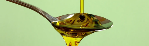 Oil dripping from a spoon against a green background