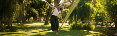 A woman is dancing in a sunny park