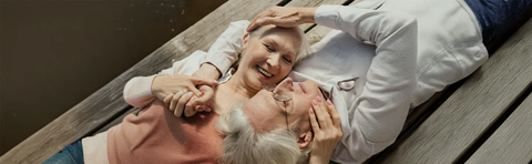 An older woman is lying on a bench with a child, laughing