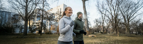 Two people are jogging through a wintery park
