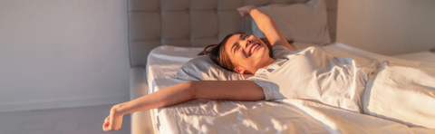 Frau streckt sich beim Aufwachen im Bett