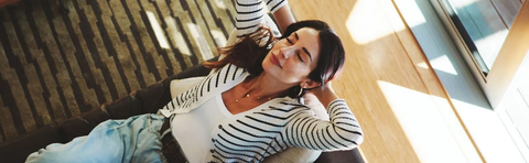 A woman is lying on the floor, stretching in the sunlight