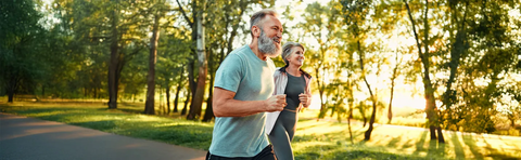 Zwei Menschen joggen durch einen sonnigen Park