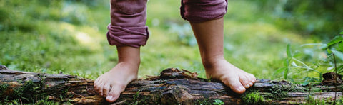 Close-up of bare feet balancing on a tree trunk