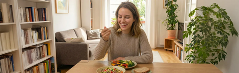 A woman is eating at a table; a bookshelf is in the background; Image note: AI-assisted content