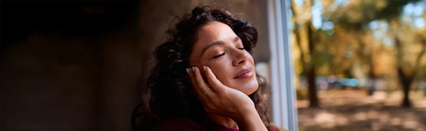A woman with her eyes closed rests her head in her hand, autumn light