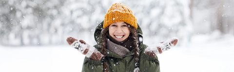 Kind in Winterkleidung wirft lachend Schnee in die Luft