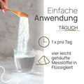 Einfache Anwendung von Pro Amino Spezial: 1 × pro Tag vier leicht gehäufte Messlöffel in Flüssigkeit; Pulver rieselt von einem Holzlöffel in ein Glas Wasser