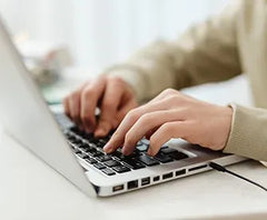 Hände tippen auf einer Laptop-Tastatur