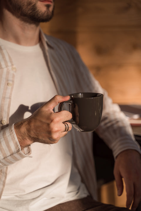 A man in a light-colored shirt is holding a cup in his hand