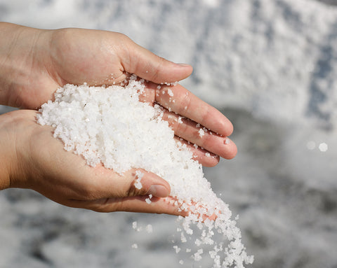 Hands let coarse sea salt trickle through their fingers