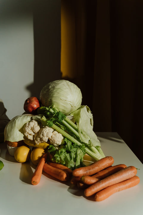 Fresh vegetables on a table: cabbage, cauliflower, carrots, and bell peppers