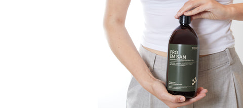 Frau hält eine Flasche TISSO Pro EM san vor ihren Bauch