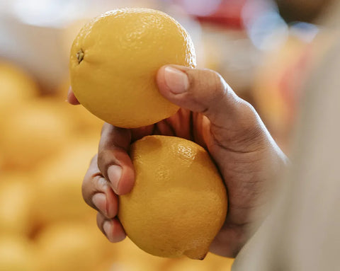 Mensch hält zwei Zitronen in der Hand
