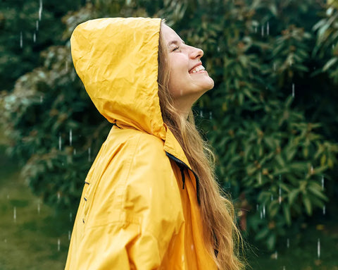 Frau steht lächelnd im Regen