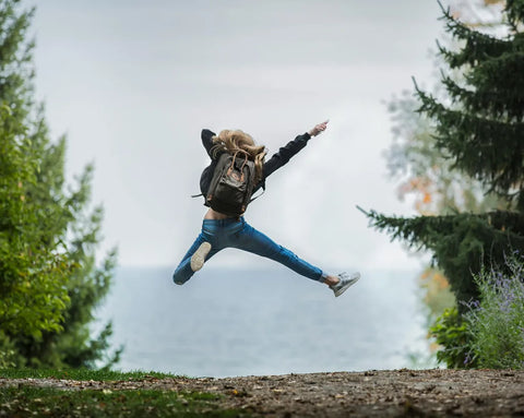 Frau mit Rucksack springt hoch