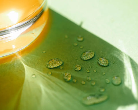Wassertropfen auf einem Tisch neben einem Glas mit Orangensaft