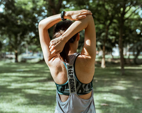 Junge Joggerin macht Dehnübungen im Park