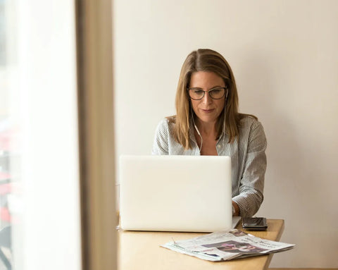 A woman wearing headphones is working intently on her laptop—a stock image representing the e-learning courses offered by the TISSO Academy